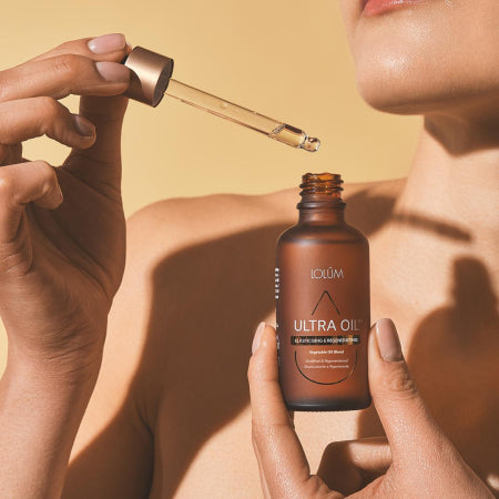 Gros plan sur la bouteille ULTRA OIL™ mettant en valeur la texture soyeuse de l’huile végétale régénératrice.