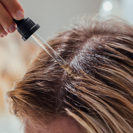 Femme aux cheveux longs et lisses posant sur fond beige, mettant en valeur une chevelure brillante et soyeuse.