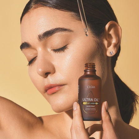 Huile ULTRA OIL LOLUM entourée de pépins de raisin, graines de lin et acide hyaluronique, illustrant son action antioxydante et illuminatrice