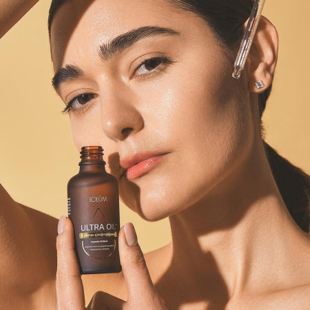 Huile ULTRA OIL™ repulpante et hydratante, flacon ambré premium présenté sur fond doux aux tons naturels